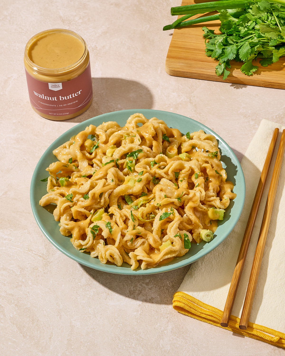 A bowl of creamy walnut butter pasta with  chili oil and green onions.
